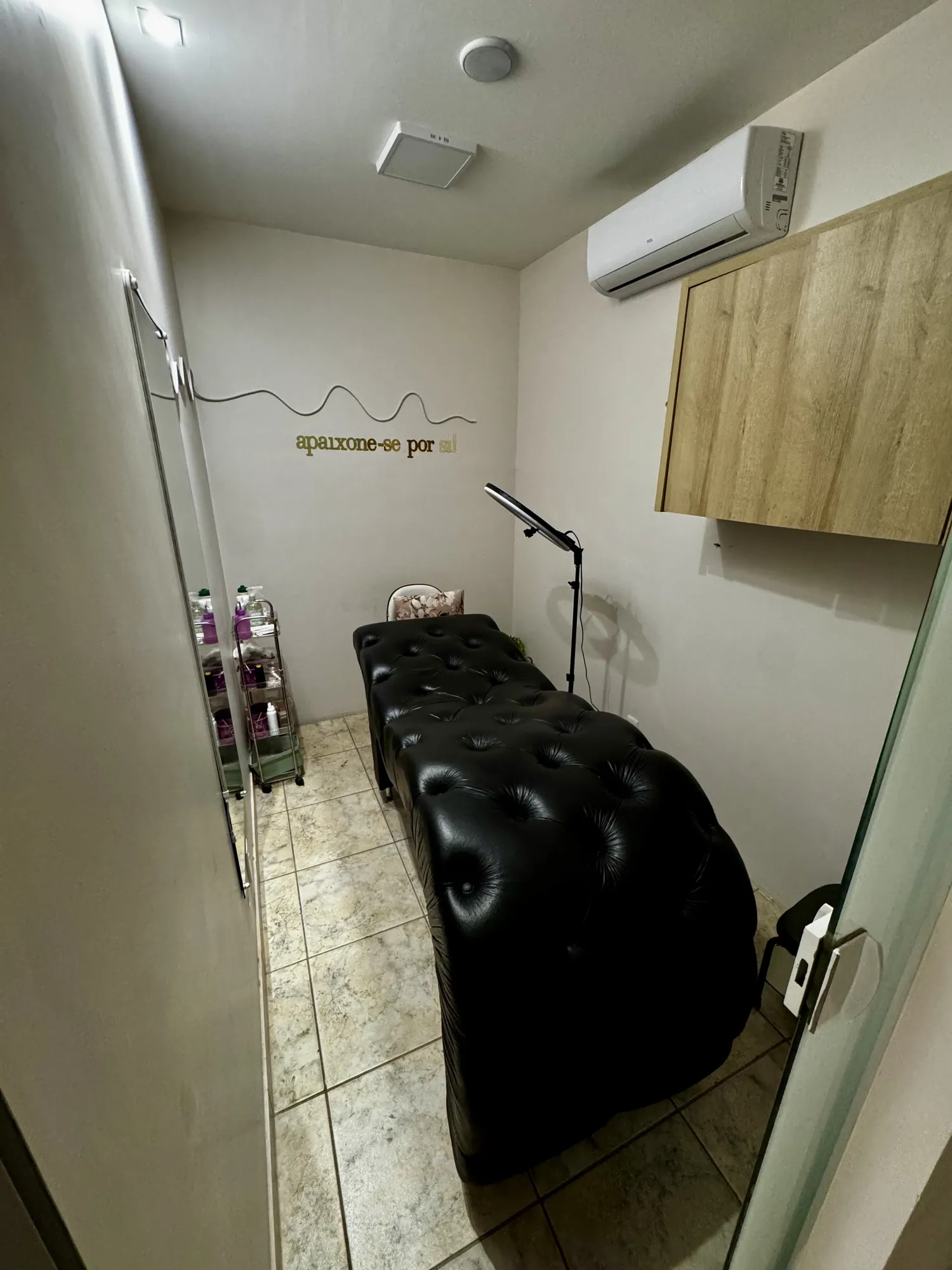 Sala de cílios e sobrancelhas com maca estofada e luz de anel